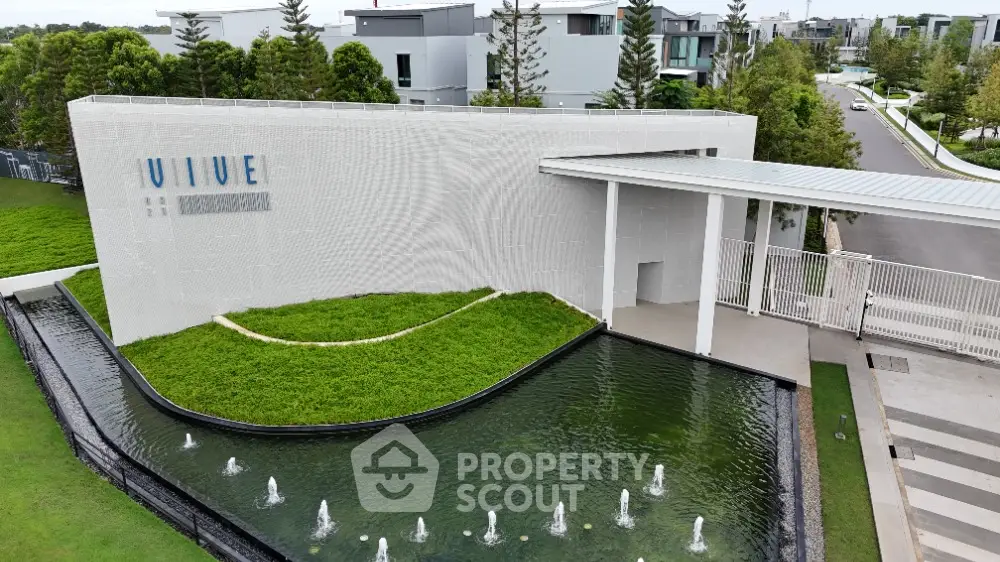 Modern residential entrance with water feature and lush greenery