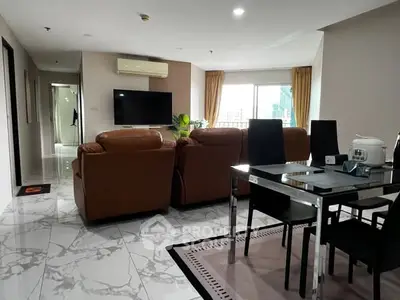 Spacious living room with modern leather sofas and dining area, featuring marble flooring and large windows.
