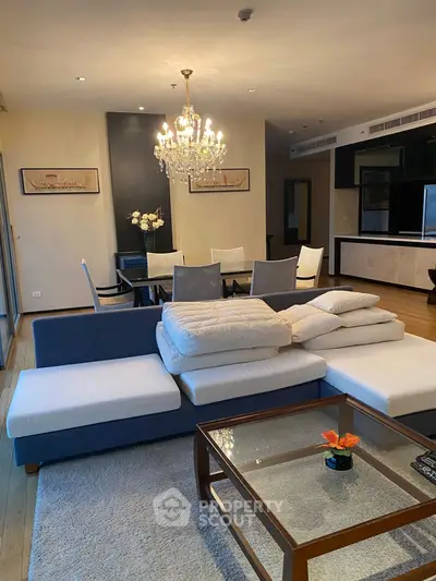 Spacious living room with elegant chandelier and modern dining area in luxury apartment.