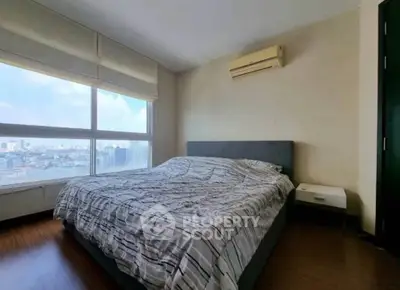 Spacious bedroom with large window offering stunning city views and modern air conditioning.