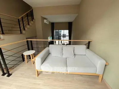 Modern loft with stylish sofa and open staircase, perfect for urban living.
