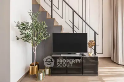 Modern living room with stylish TV stand and decorative plant under staircase