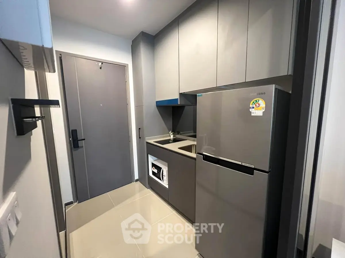 Modern compact kitchen with sleek cabinetry and stainless steel fridge in urban apartment.