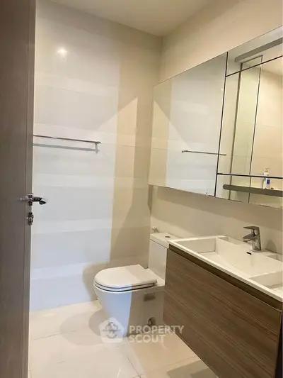 Modern bathroom with sleek fixtures and minimalist design, featuring a wall-mounted vanity and large mirror.