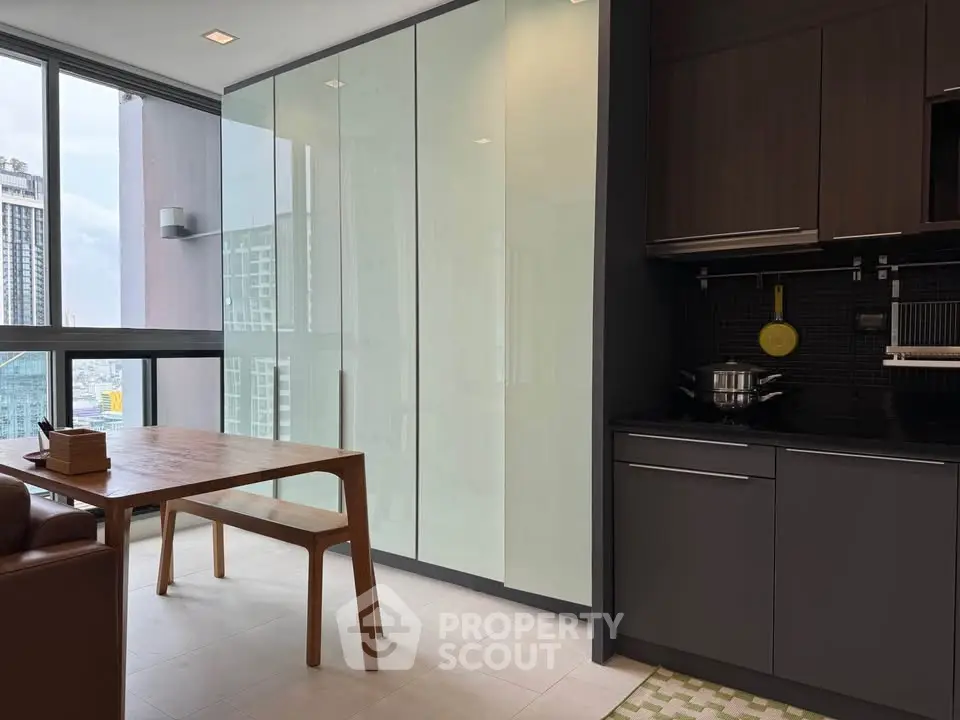 Modern kitchen with sleek cabinetry and dining area in high-rise apartment.
