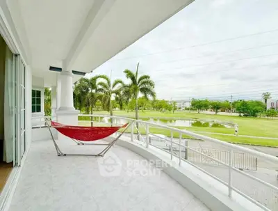 Spacious balcony with hammock overlooking lush green park and serene pond.