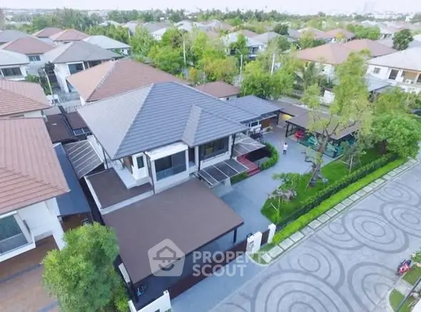 Aerial view of a modern residential neighborhood with lush greenery and spacious driveways.