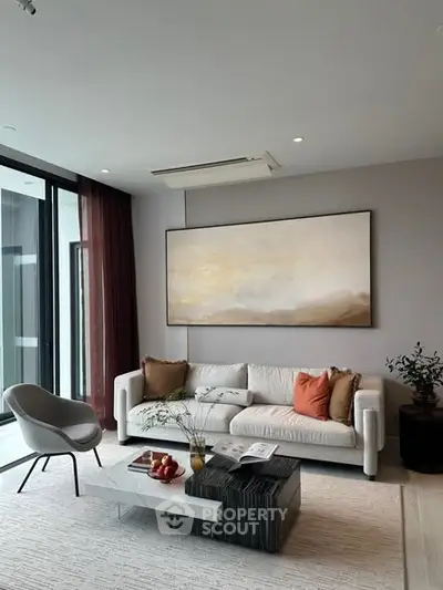 Modern living room with elegant decor, featuring a cozy sofa, stylish armchair, and large artwork on the wall.
