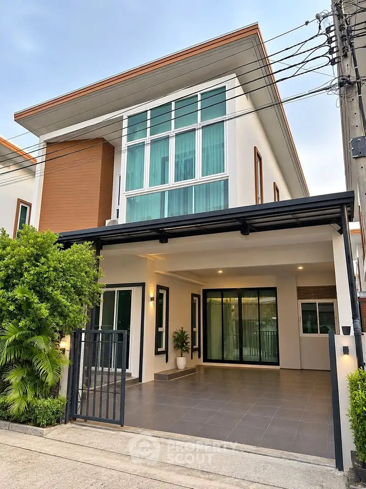 Modern two-story house with large windows and a spacious driveway, perfect for family living.