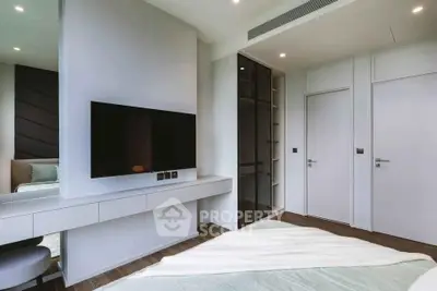 Modern bedroom with sleek design, featuring a wall-mounted TV and stylish storage solutions.