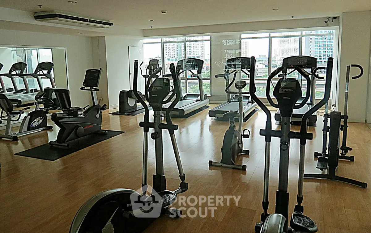 Spacious gym with modern equipment and city view, ideal for fitness enthusiasts.