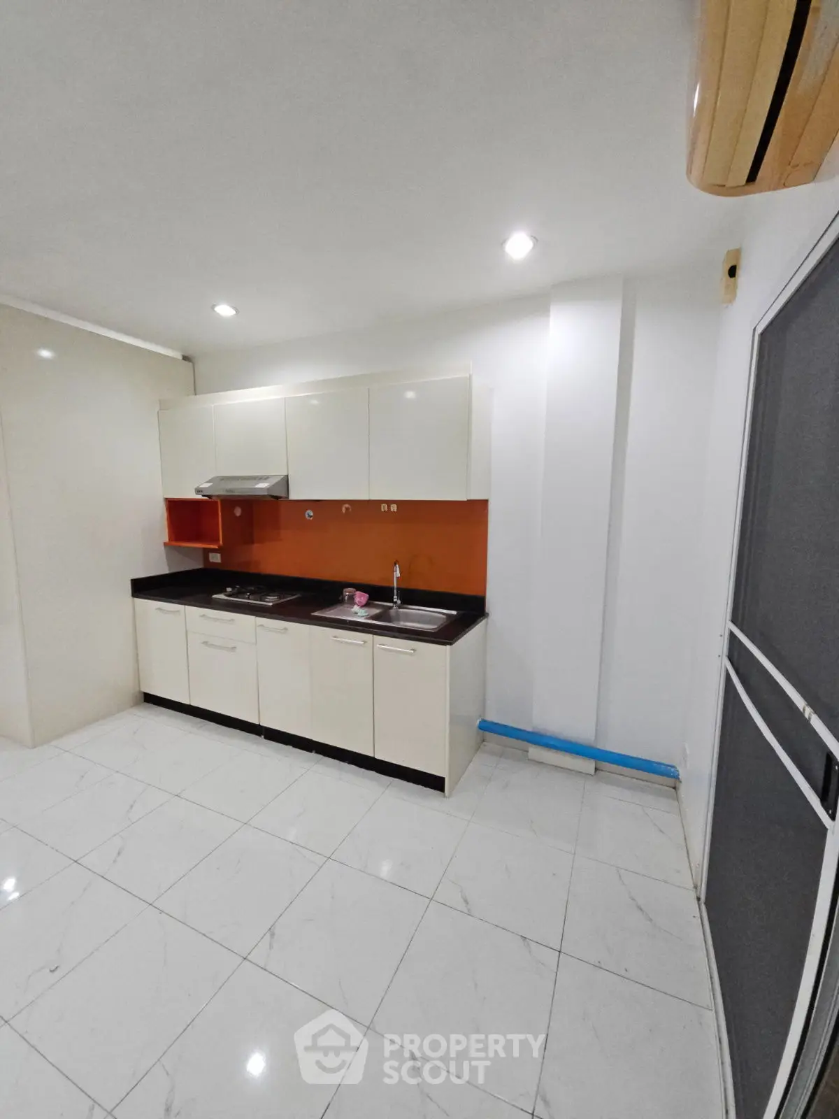 Modern kitchen with sleek cabinets and bright lighting, featuring a compact design and tiled flooring.