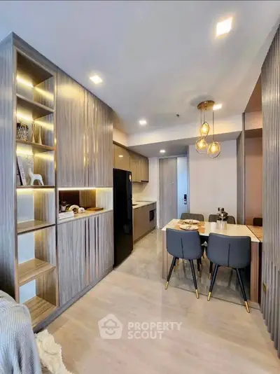 Modern open-layout kitchen and dining area with stylish lighting and wooden cabinetry.