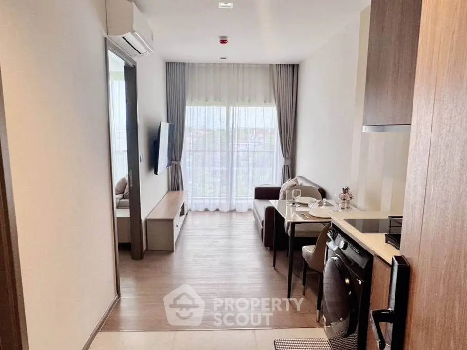 Modern living room with open kitchen in a stylish apartment, featuring elegant decor and natural light.