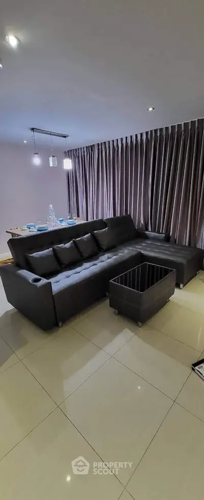 Modern living room with sleek black sectional sofa and elegant curtains