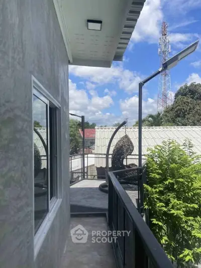 Charming balcony with modern railing and scenic view of lush greenery and clear blue sky.