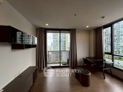 Modern living room with large windows and city view, featuring sleek furniture and wooden flooring.