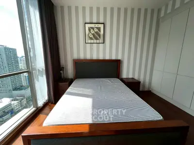 Modern bedroom with large window and city view, featuring stylish furniture and ample natural light.