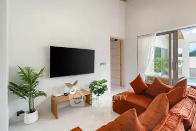 Luxurious modern living room with plush orange sofa and large TV, overlooking a serene pool view.