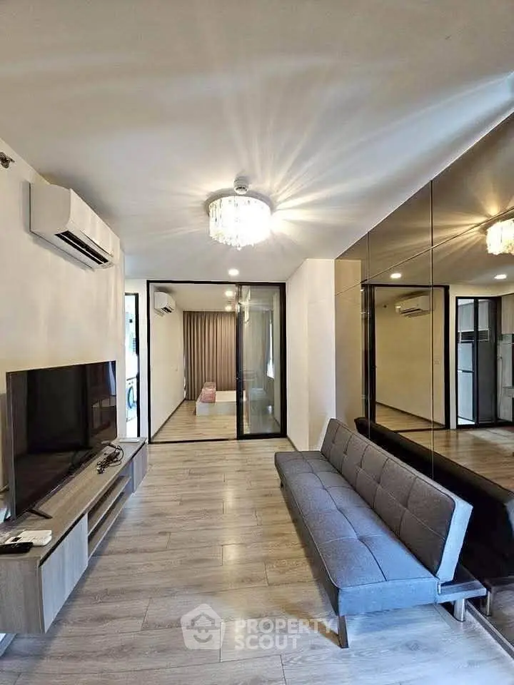 Modern living room with sleek design, mirrored wall, and cozy sofa in a stylish apartment.