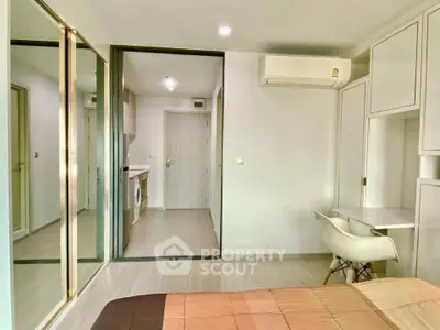Modern bedroom with mirrored closet doors and compact study area in a stylish apartment.