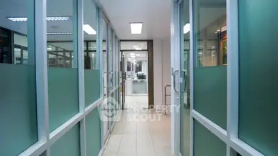 Spacious commercial office corridor with glass partitioned cubicles, offering a modern and collaborative work environment.