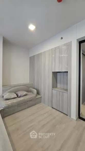 Modern bedroom with sleek built-in storage and cozy bed in minimalist design.