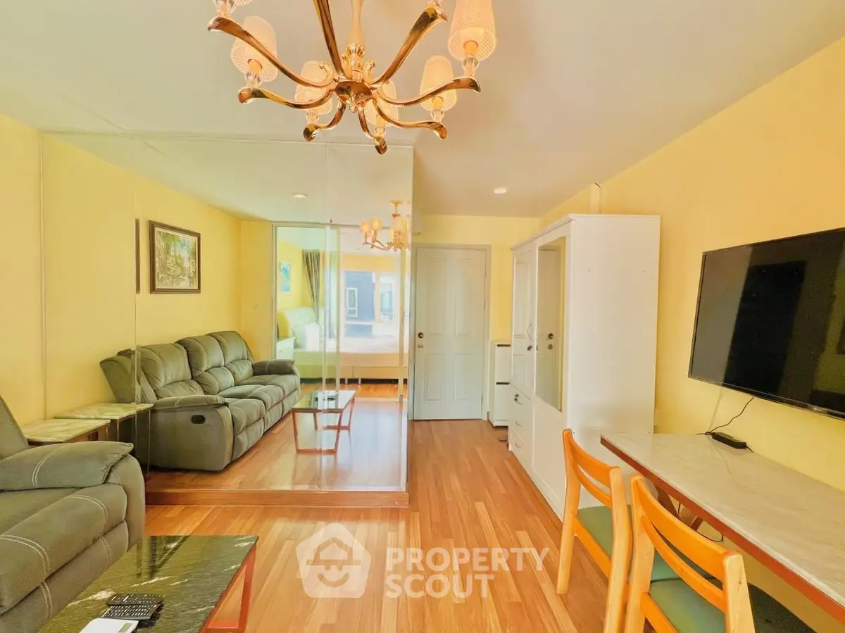 Spacious living room with elegant chandelier and modern furnishings in a cozy apartment.