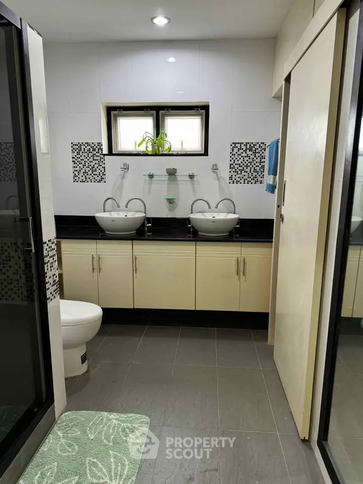 Modern bathroom with dual sinks and stylish black and white tile accents.