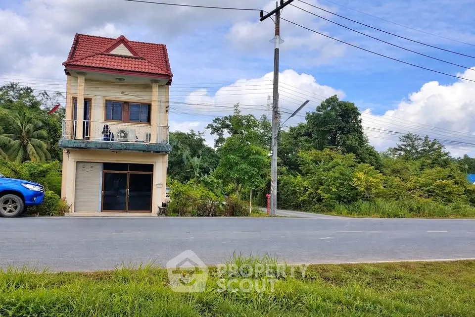 Charming two-story house with red roof and lush greenery, perfect for serene living.