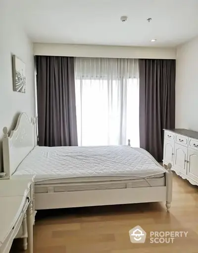 Elegant bedroom with classic white furniture and large window draped in dark curtains, offering a serene and sophisticated sleeping space.