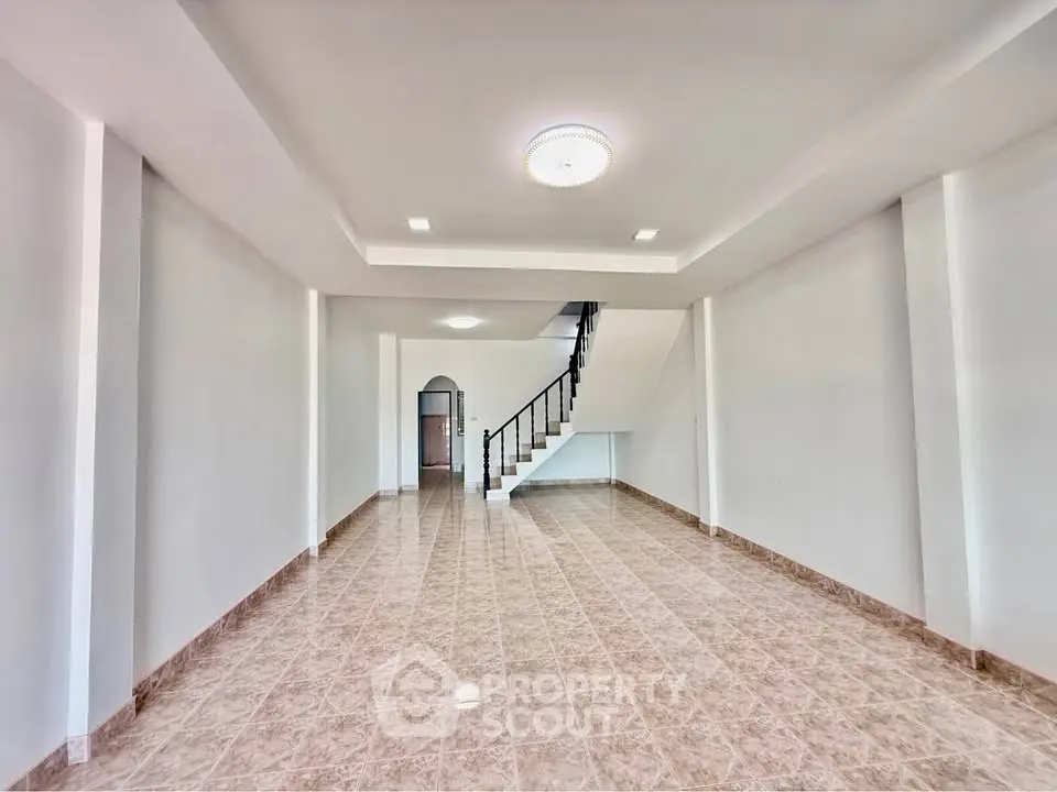 Spacious open-plan living area with modern staircase and elegant ceiling light.