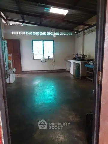 Spacious kitchen with open layout and natural light, featuring basic appliances and rustic charm.