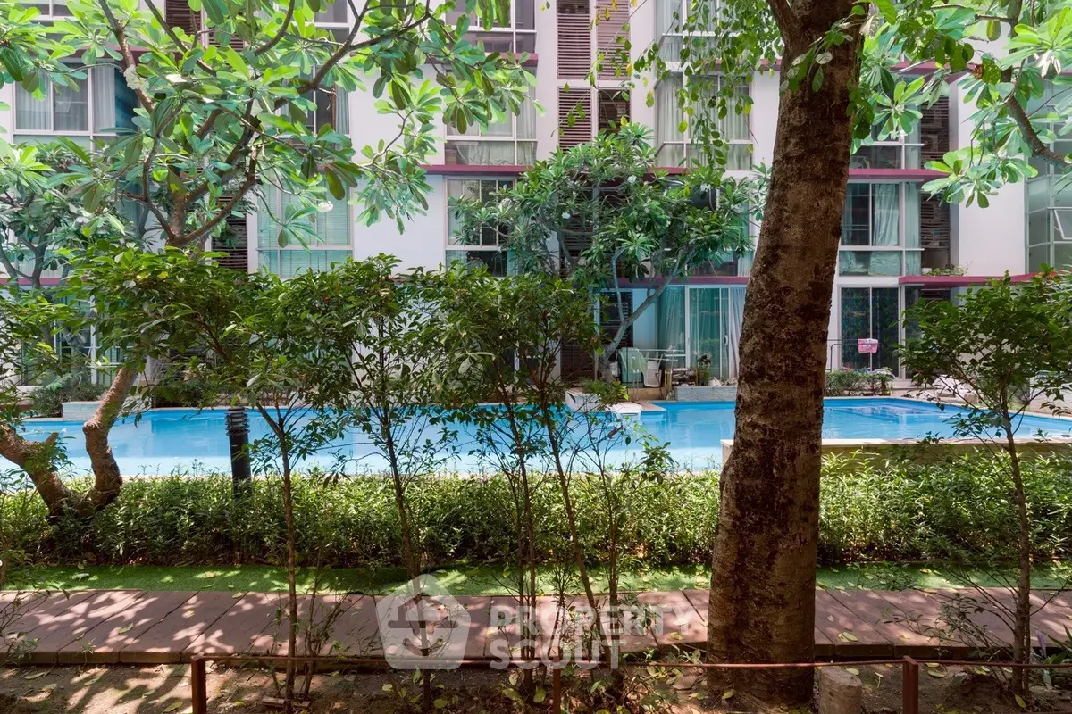 Luxurious residential building with serene pool and lush greenery view.