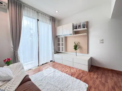 Modern living room with elegant decor and natural light, featuring hardwood floors and stylish furniture.