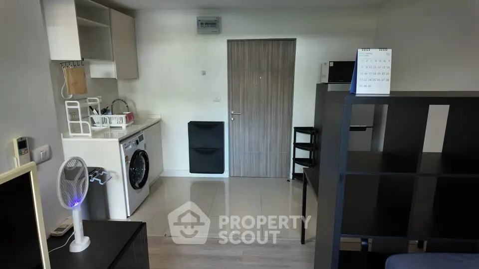 Modern studio apartment with compact kitchen and washing machine, ideal for urban living.