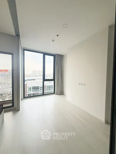 Spacious modern living room with large windows and city view, perfect for urban living.
