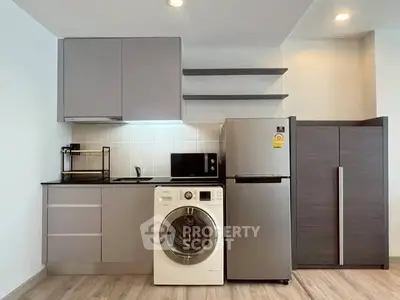 Modern kitchen with sleek cabinets, washing machine, and stainless steel fridge.
