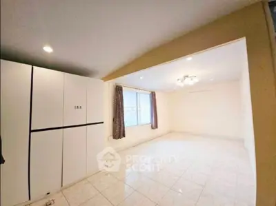 Spacious living room with large window and modern lighting, perfect for cozy gatherings.