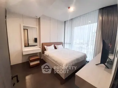 Modern bedroom with city view, featuring sleek furniture and large windows for natural light.