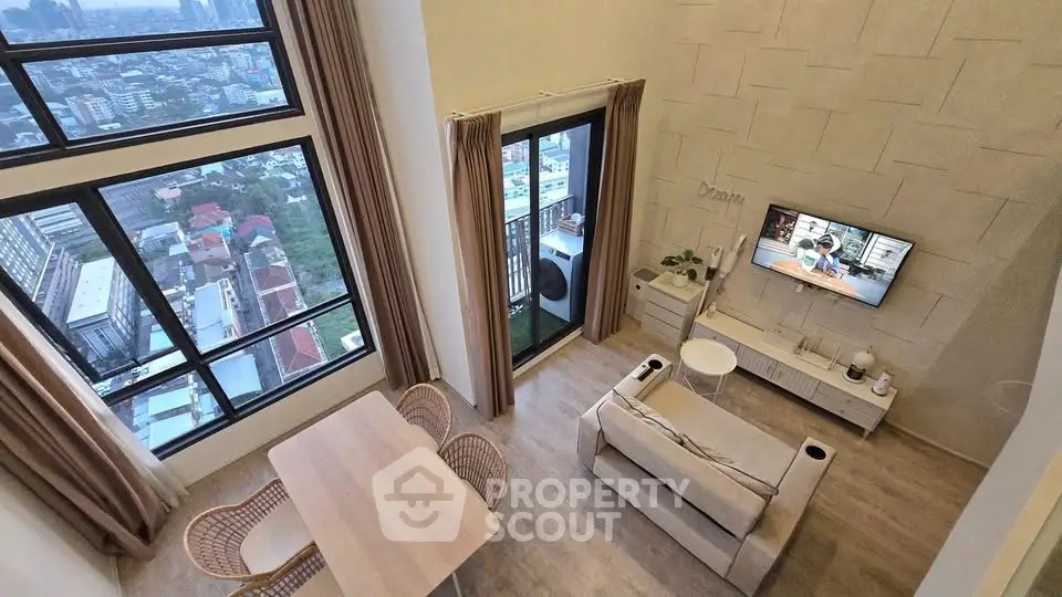 Modern living room with high ceiling and city view from large windows and balcony.
