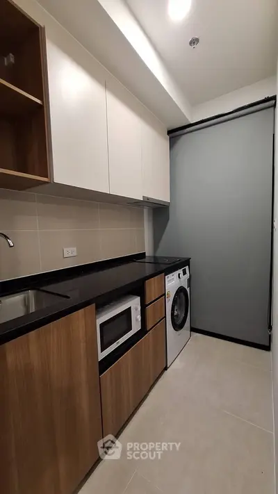 Modern kitchen with sleek cabinetry, built-in microwave, and washing machine in compact layout.