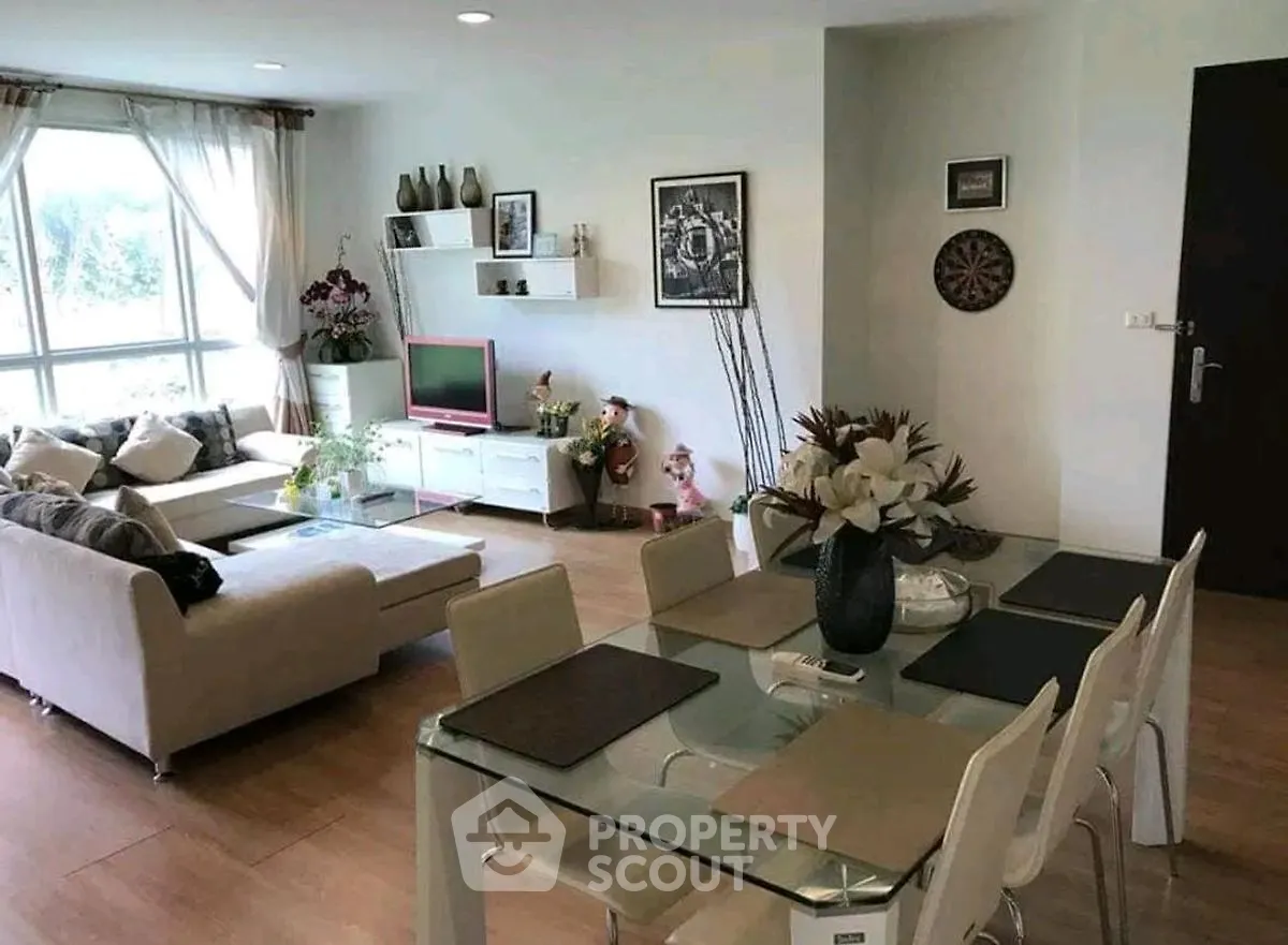 Spacious living room with modern decor and dining area, featuring large windows and stylish furniture.
