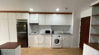 Modern kitchen with sleek cabinetry, stainless steel appliances, and in-unit washing machine.