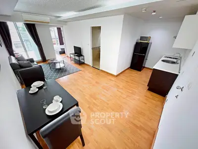 Spacious open-plan living room with modern kitchen and dining area, featuring wooden flooring and natural light.