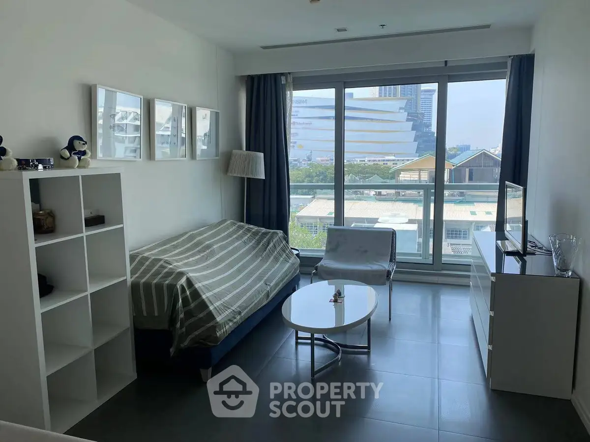Modern living room with large window and city view, featuring minimalist furniture and decor.