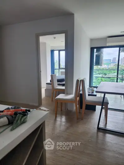 Modern apartment interior with open layout and balcony view, featuring stylish dining area and natural light.