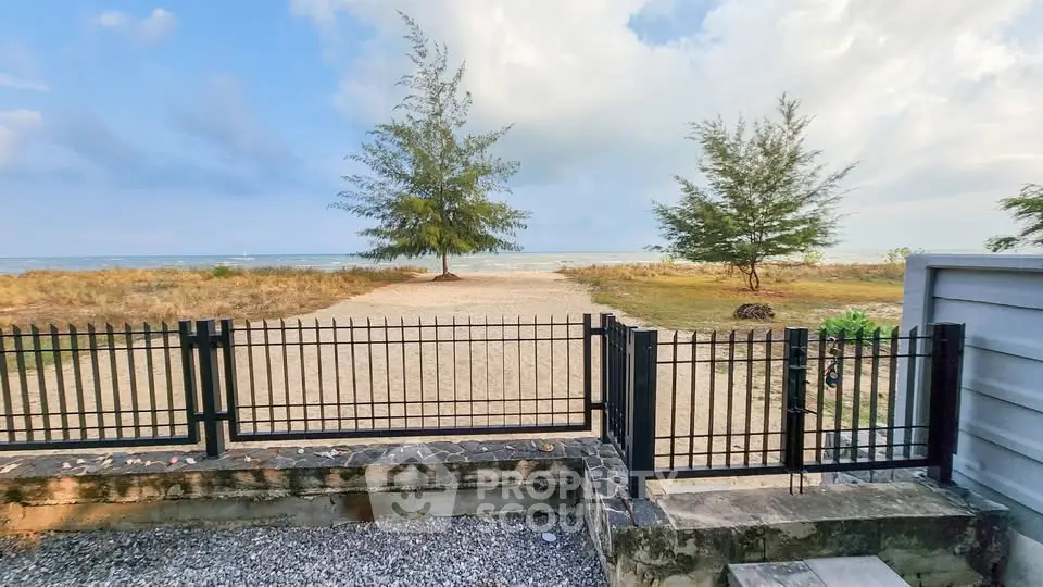 Stunning beachfront view with sandy path and lush trees, perfect for serene living.