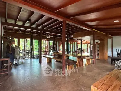 Spacious open-plan living area with wooden beams and large windows offering lush garden views.