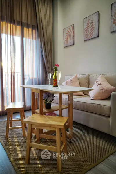 Cozy living room with elegant decor and natural light, featuring a stylish sofa and wooden dining set.